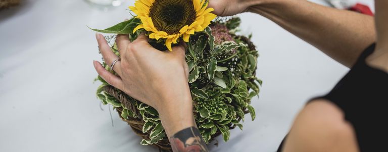 Eine Frau gestaltet ein Blumenarrangement mit einer Sonnenblume